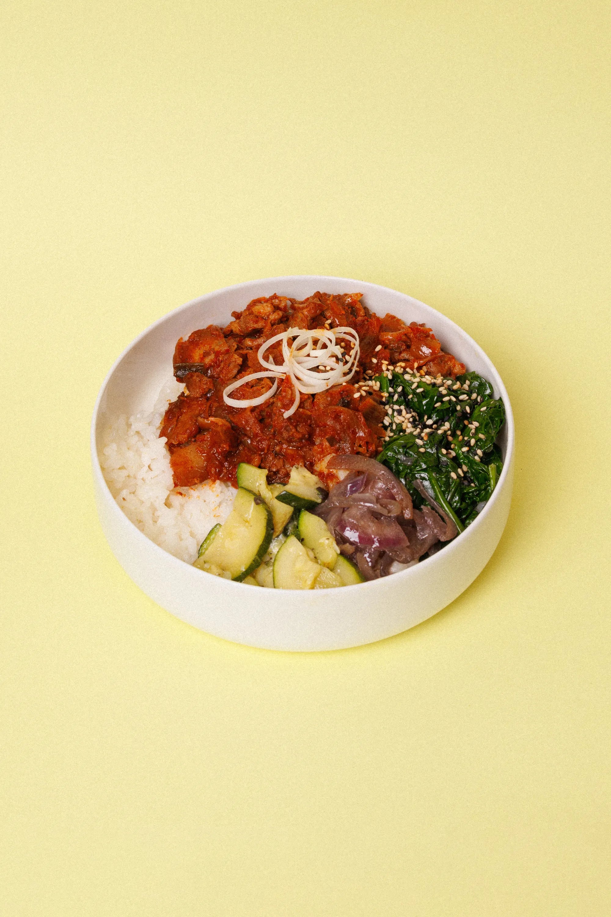 Photo of Korean rice dish served on a white plate on yellow background.