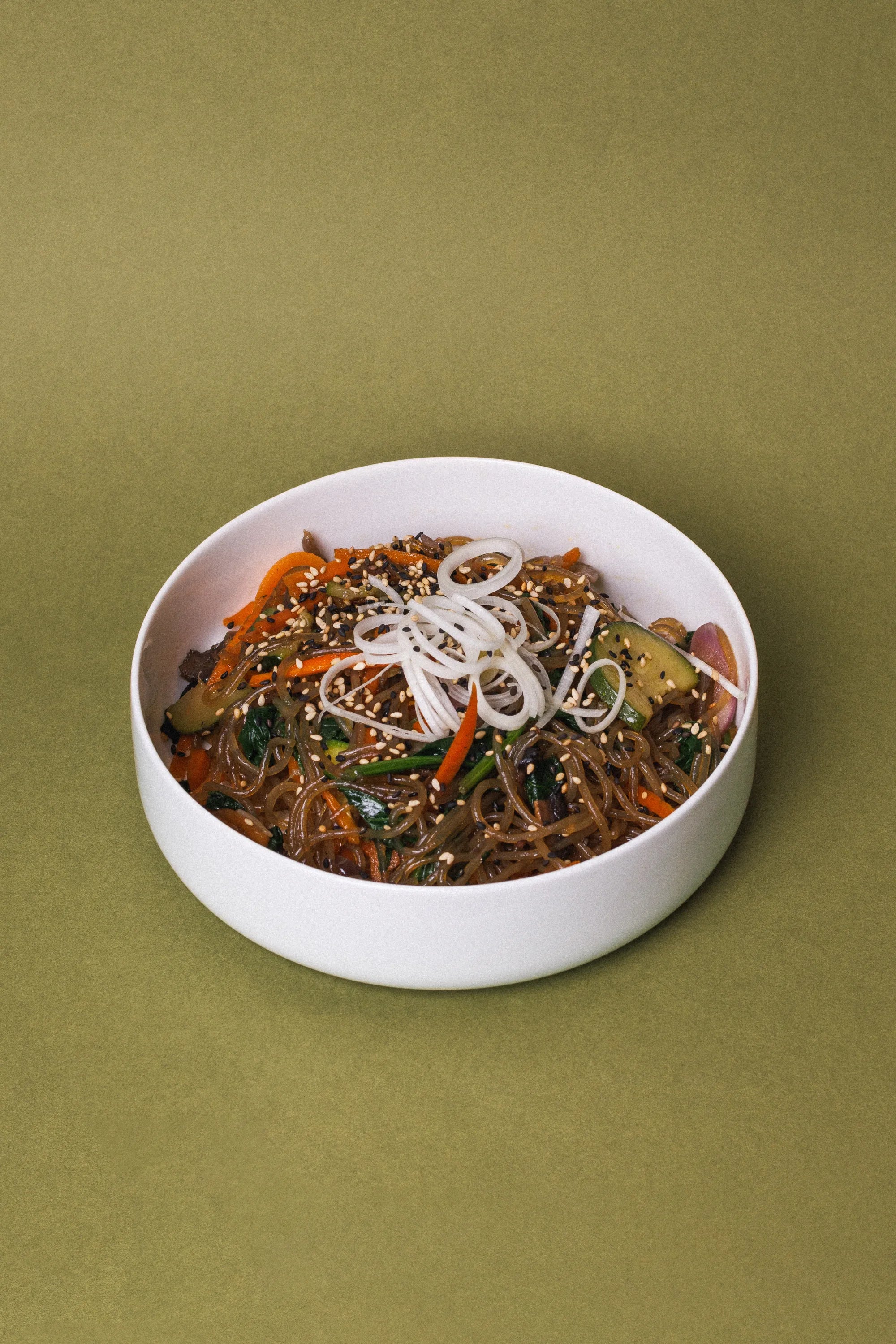 Photo of Korean noodle dish Japchae served in a white bowl