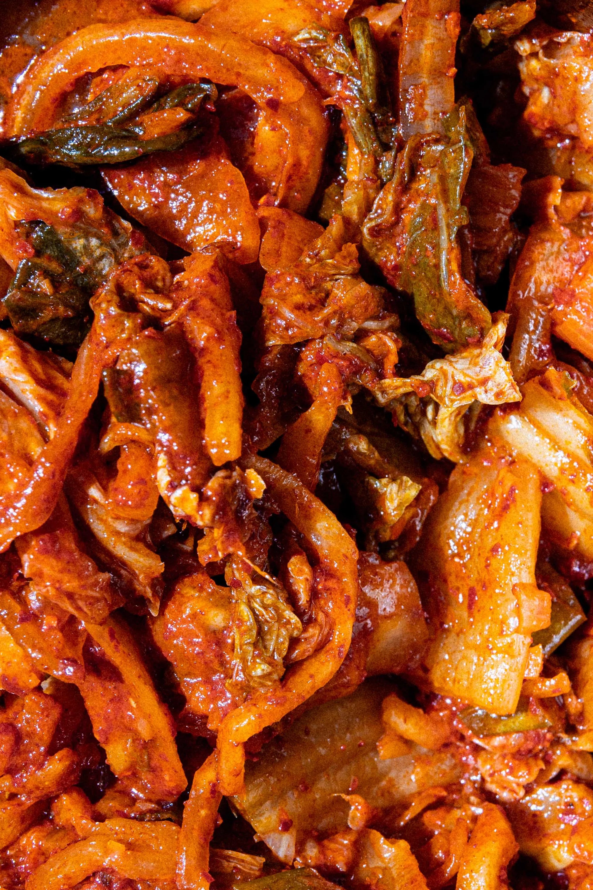 Close-up of a spicy Korean kimchi dish with red chili paste, cabbage, and onions.